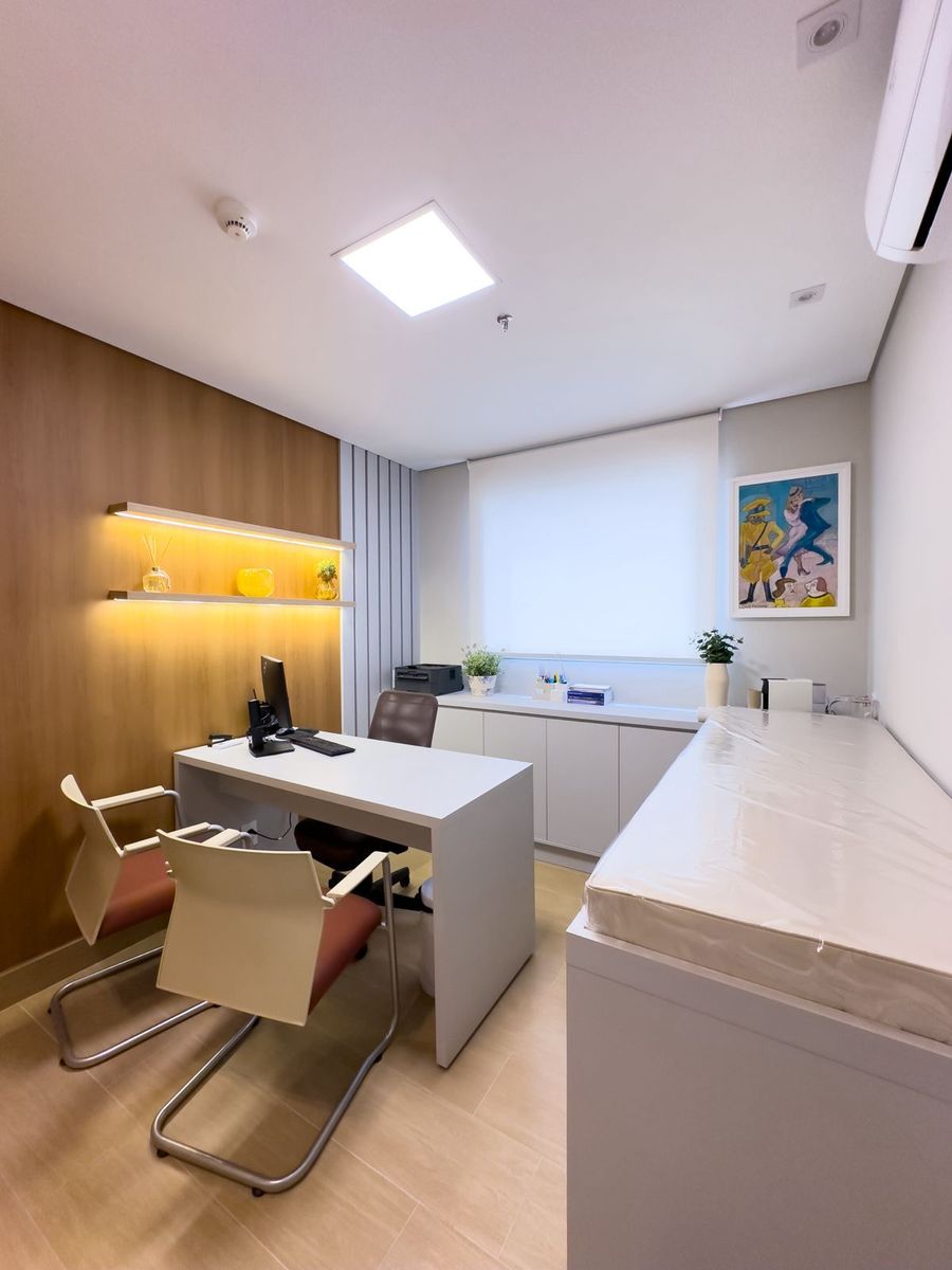 Sala de atendimento com mesa, cadeiras e maca